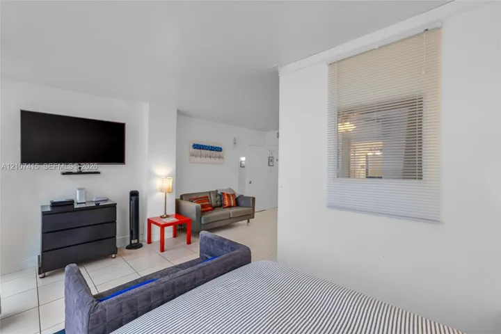 Neutral wall-to-wall tile flooring and a window featuring horizontal blinds
