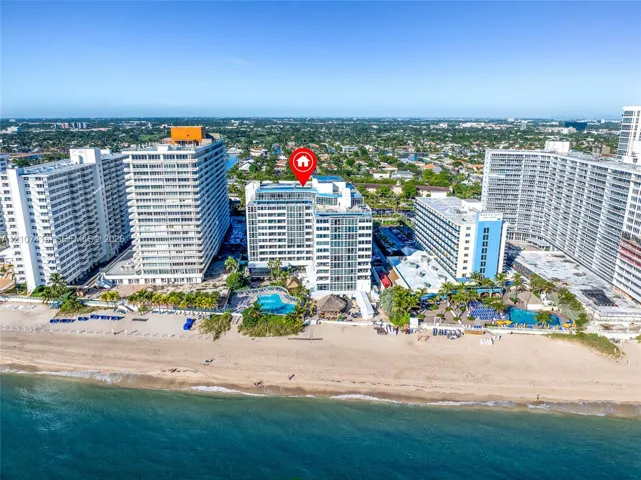 Direct oceanfront high-rise building featuring a rooftop pool, ground-level swimming pool, private beach access, and extensive glass-paneled exterior