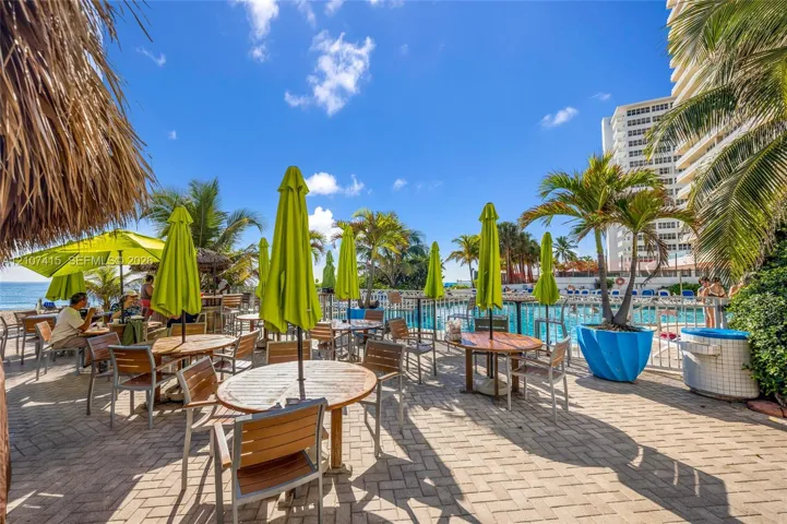 Paver-stone patio featuring an in-ground swimming pool, metal perimeter fencing, and mature palm trees