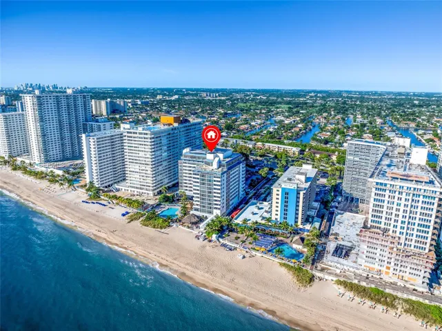 Aerial perspective featuring direct oceanfront positioning, expansive coastal sand beach, and proximity to regional waterways