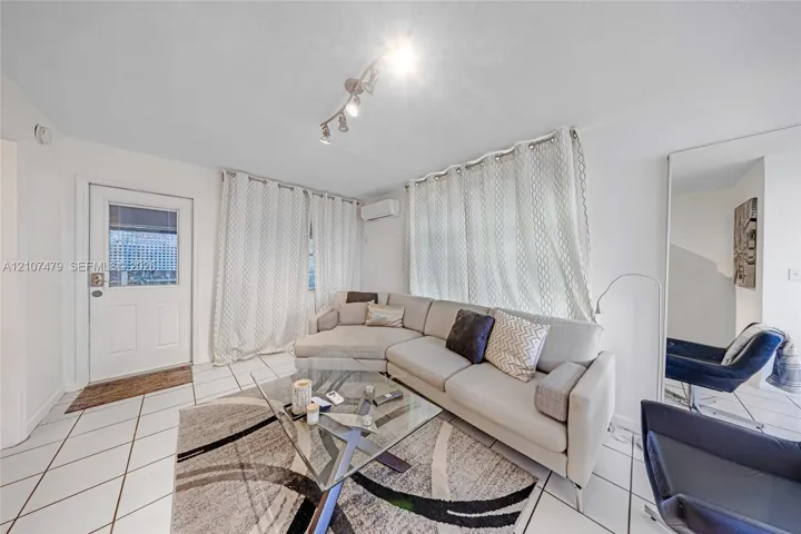 Interior space featuring white tiled flooring, a mounted ductless mini-split HVAC unit, and track lighting