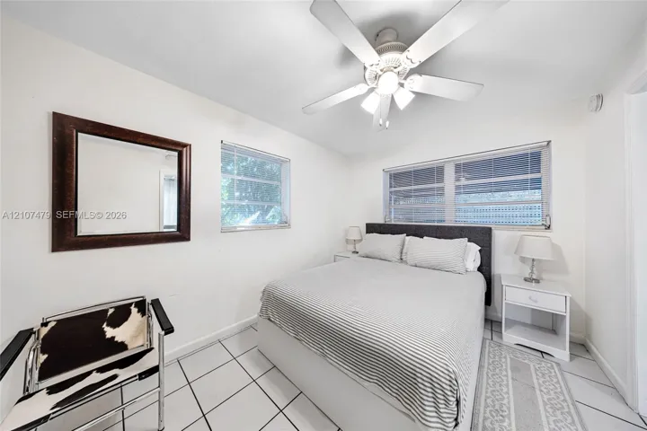 Interior space featuring white tile flooring, white-finish ceiling fan with integrated lighting, and multiple windows