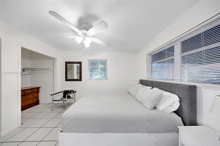 Interior space featuring white ceramic tile flooring, a multi-blade ceiling fan with integrated lighting, and horizontal window blinds