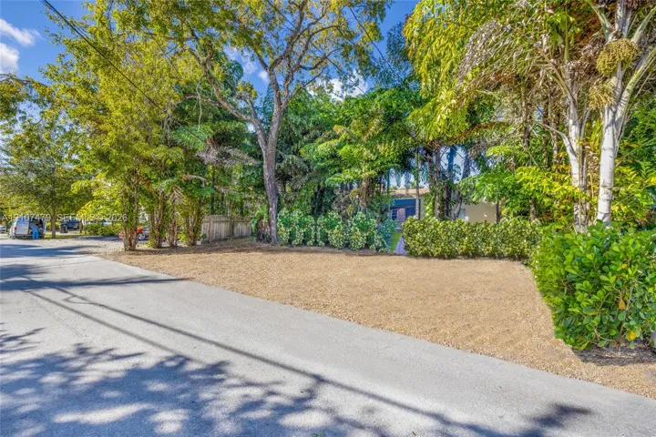 Level lot featuring mature trees, established shrubbery, and a paved street frontage