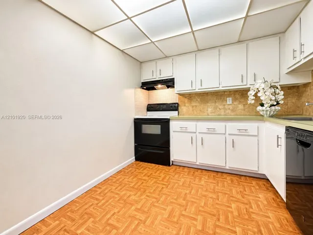 Kitchen featuring white cabinetry, wood-finish flooring, a patterned tile backsplash, and recessed ceiling lighting