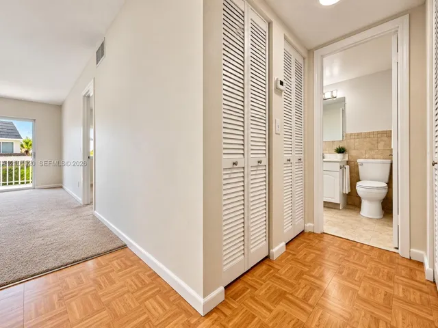 Parquet wood-finish flooring, dual bi-fold louvered closets, and neutral interior paint palette