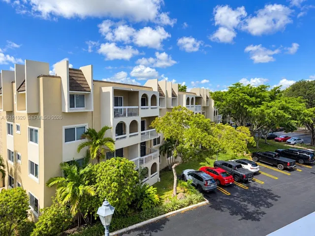 Multi-story stucco exterior featuring arched balconies, white railings, and dedicated off-street parking