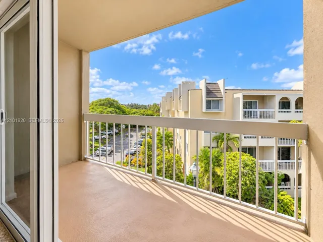 Covered balcony featuring a concrete floor surface and a white metal railing