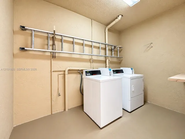 Utility space featuring painted concrete walls, smooth-finish flooring, a ceiling-mounted light fixture, and an integrated wall-mounted equipment rack