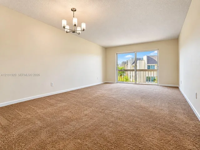 Neutral-toned carpeting, five-light chandelier with frosted glass shades, and sliding glass door with external balcony access