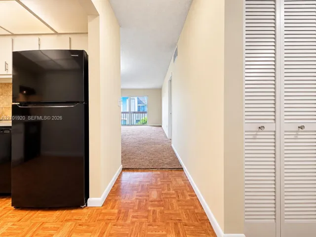 Parquet wood flooring, black top-mount refrigerator, and white louvered-style closet doors