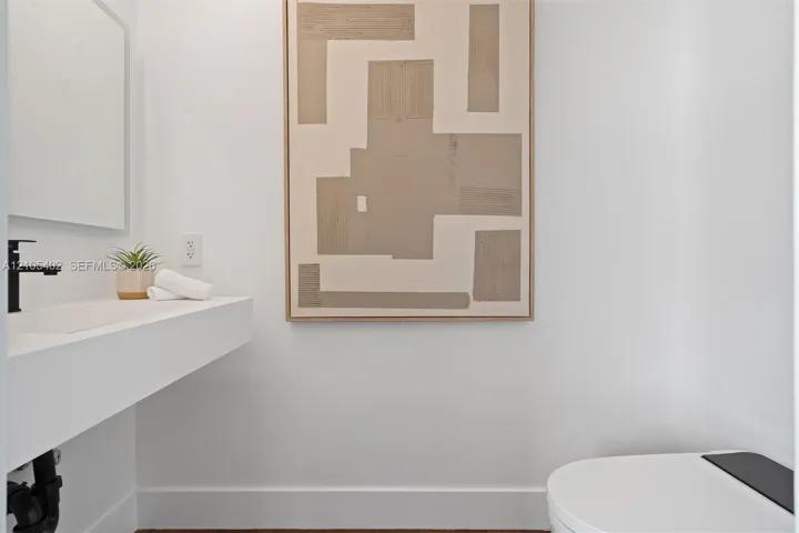 Wall-mounted floating sink with integrated basin, matte black faucet, and modern elongated toilet