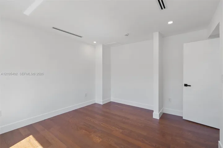 Neutral interior featuring wood-finish flooring, recessed lighting, and a multi-panel door with matte black hardware