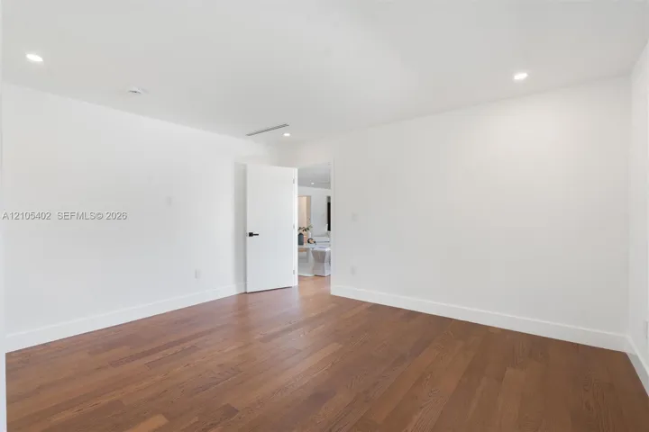 Interior room featuring wood-finish flooring, recessed lighting, and a white interior door with matte black hardware