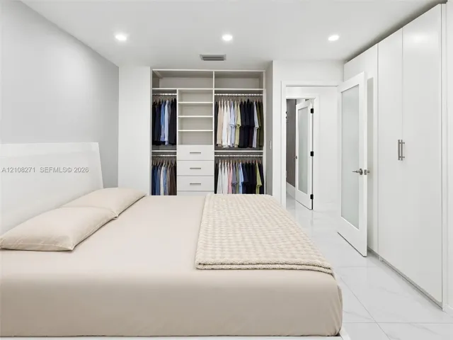 Built-in wardrobe system with integrated shelving and drawers, floor-to-ceiling cabinetry, recessed lighting, and large-format tile flooring