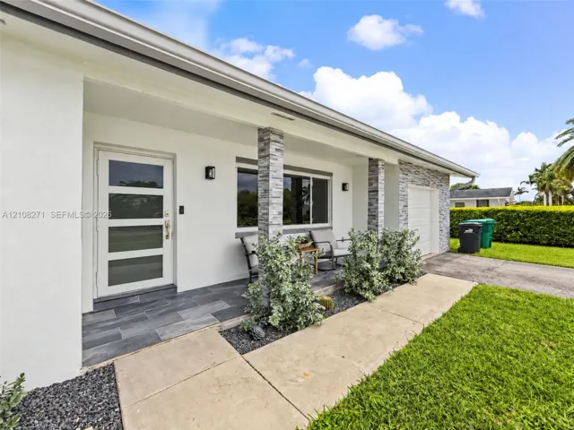 Exterior featuring a covered porch with large-format slate-finish tile flooring, stacked stone column cladding, a multi-pane glass entry door, and a matching stone-accented facade