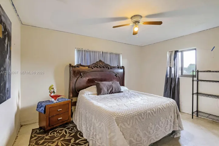 Room featuring neutral-toned walls, a central ceiling fan with integrated lighting, and natural light provided by a dual-pane window