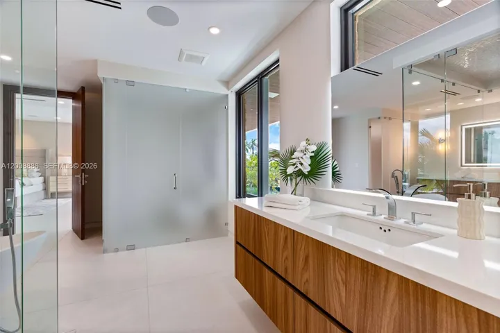 Built-in wood-paneled sauna featuring a glass-door entrance, accompanied by a walk-in shower with a mosaic-tiled accent wall, glass enclosure, transom window, and matte black fixtures