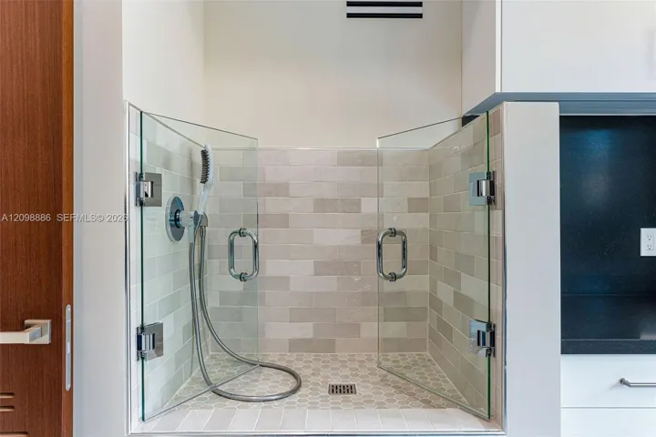 Glass-enclosed station featuring a handheld shower fixture, subway-tile wall surround, hexagonal floor tile, and polished chrome hardware