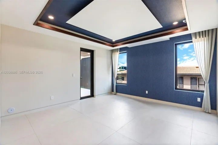Tray ceiling with recessed lighting, large-format tile flooring, blue textured accent wall, and glass-paneled exterior door