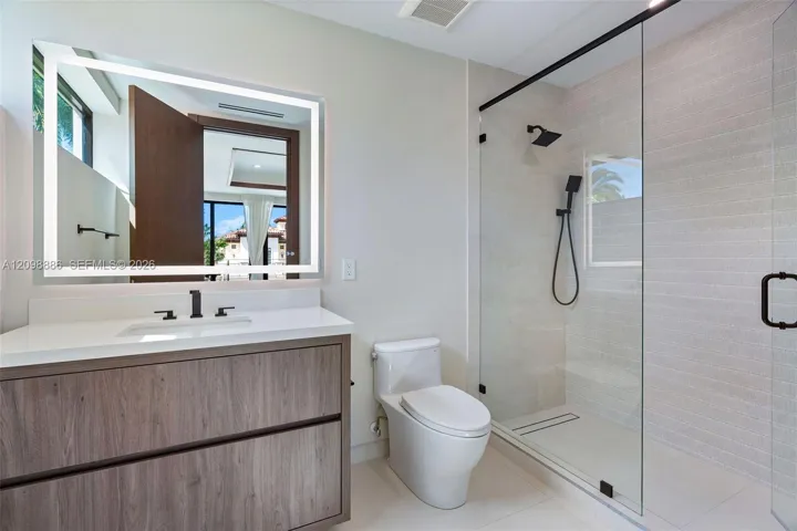 Wood-finish floating vanity with a quartz countertop, backlit LED mirror, and matte black plumbing fixtures