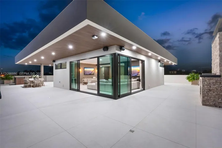 Expansive roof deck featuring large-format tile flooring, recessed overhead lighting, a covered exterior area with wood-finish ceiling, and sliding glass wall panels