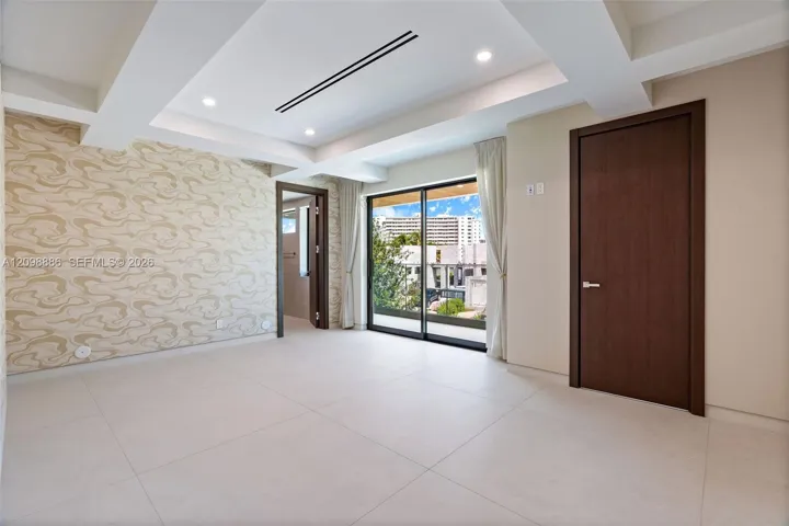 Tray ceiling with recessed lighting, large-format tile flooring, textured wall covering, and sliding glass doors with external access