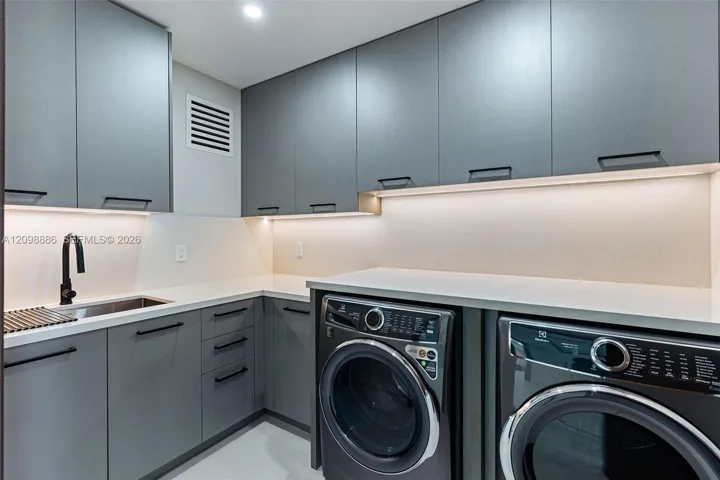 Modern cabinetry with matte hardware, light-toned countertop, undermount sink with a matte black faucet, and under-cabinet integrated lighting