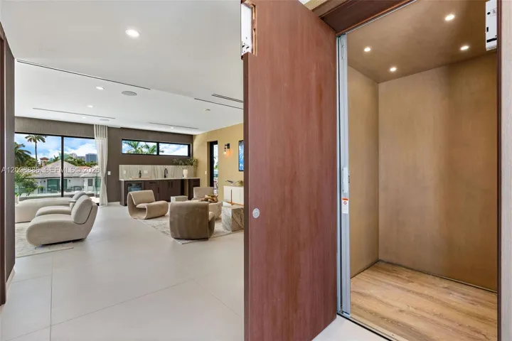 Private elevator with wood-panel interior finishes, large-format tile flooring, recessed ceiling lighting, and floor-to-ceiling glass sliding doors