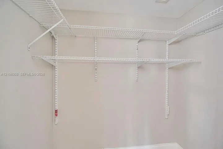 Wall-mounted white wire shelving system featuring tiered storage levels and adjustable support tracks