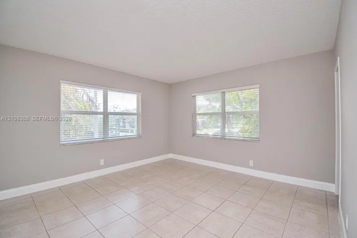 Neutral-toned interior featuring large windows, light-colored tile flooring, and a textured ceiling finish