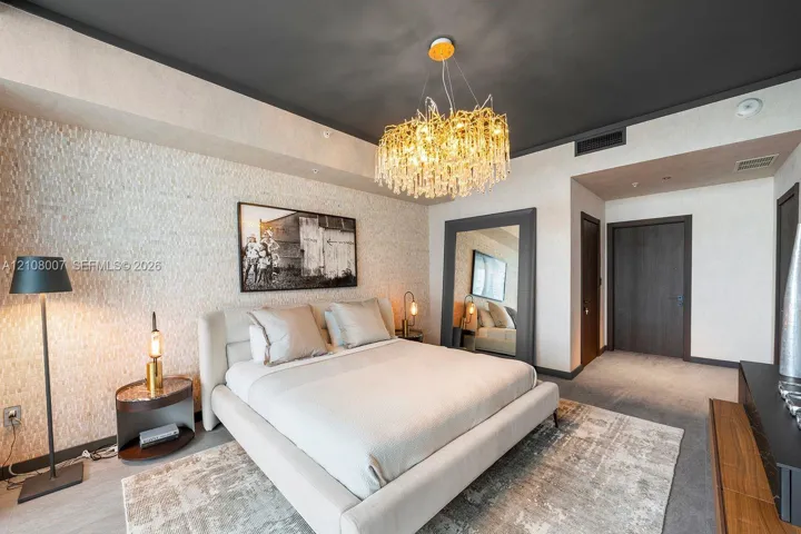 Textured stone feature wall with a contrasting dark ceiling, statement multi-tiered crystal chandelier, and dark-finish paneled interior doors