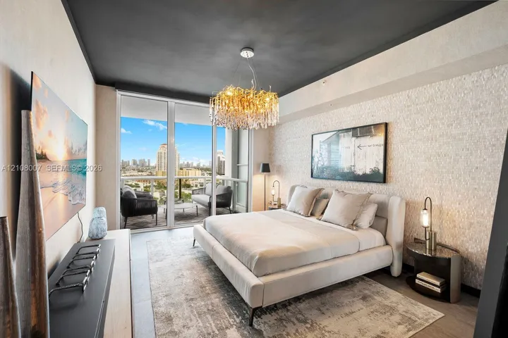 Textured stone accent wall, floor-to-ceiling glass paneling, private balcony, and decorative crystal chandelier