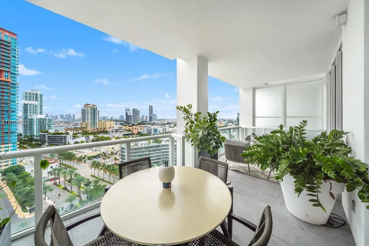 Covered balcony featuring grey tile flooring and a glass railing with metal trim