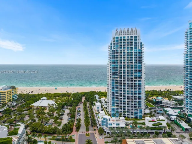 High-rise tower featuring glass-paneled balconies and a reinforced concrete structure, situated in proximity to the coastline