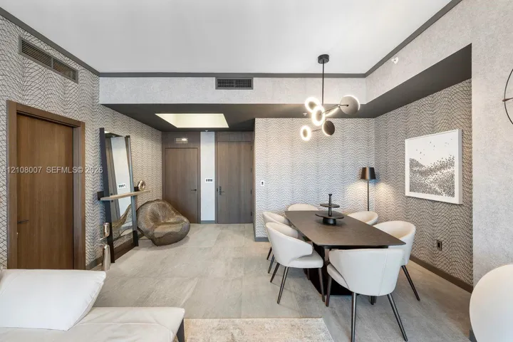 Textured wall coverings, matte-finish tile flooring, recessed ceiling lighting, and a multi-arm sculptural chandelier