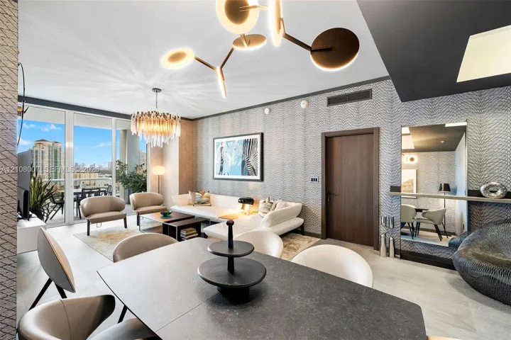 Floor-to-ceiling windows, modern multi-tiered chandelier, patterned wall treatment, wood-finish interior door, and tile flooring