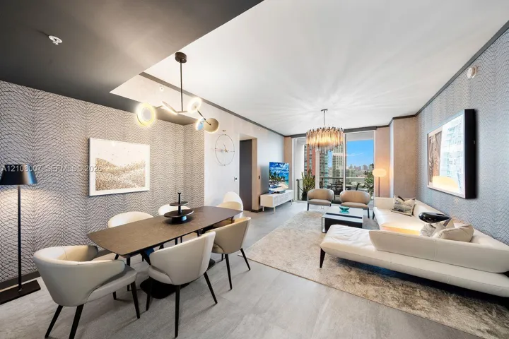 Open-concept living area featuring textured wall coverings, multi-arm contemporary pendant lighting, recessed ceiling architecture, and large-format tile flooring