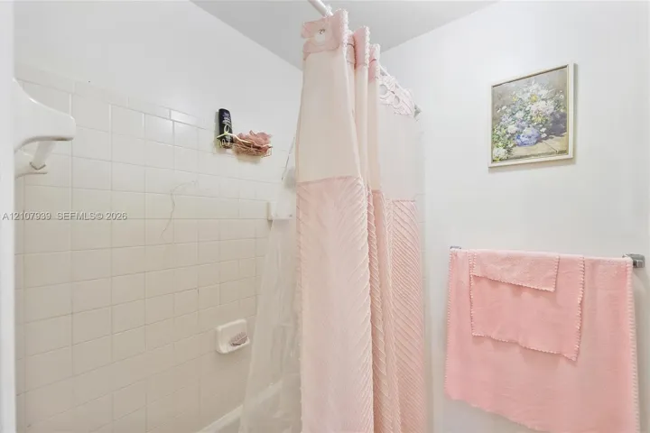 Tub enclosure featuring white ceramic wall tile and a recessed soap dish
