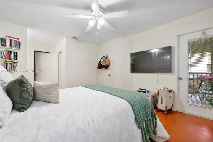 Wood-finish flooring, ceiling fan with integrated lighting, and glass-paneled door with exterior access