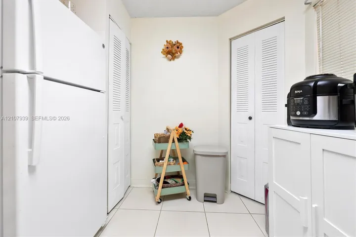 Tile flooring, two sets of white louvered-panel closets, and white cabinetry