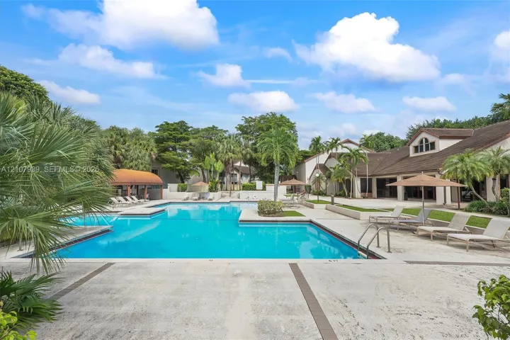 Swimming pool with stone-tiled decking, integrated landscaping, and surrounding structures