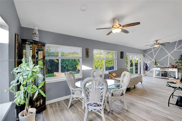 Open-concept room featuring wood-finish flooring, recessed lighting, dual ceiling fans, geometric wall detailing, and expansive windows