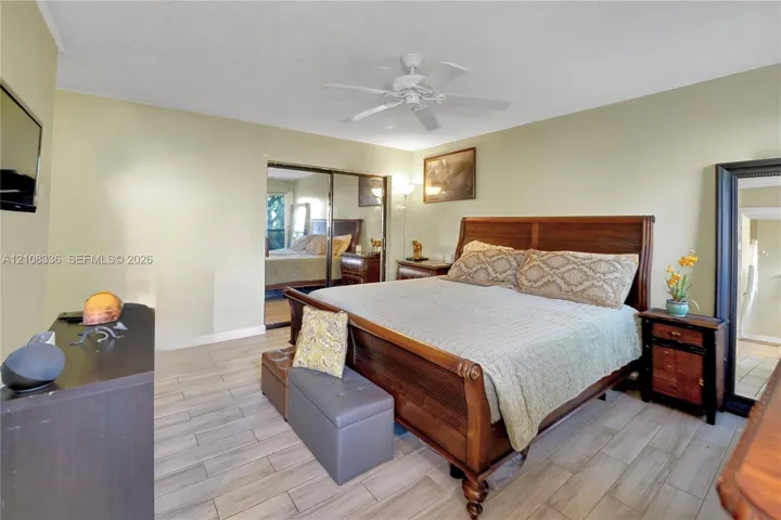 Neutral-toned walls featuring wood-finish tile flooring, ceiling fan with integrated lighting, and mirrored closet doors