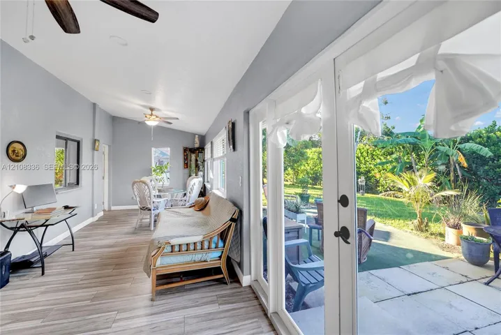 Sunroom featuring wood-finish flooring, recessed lighting, dual ceiling fans, and full-length glass panel doors opening to a paved patio