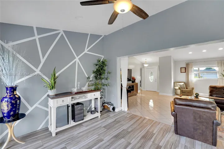 Geometric accent wall featuring a matte gray finish with white linear detailing, wood-finish flooring, and ceiling fan with integrated lighting
