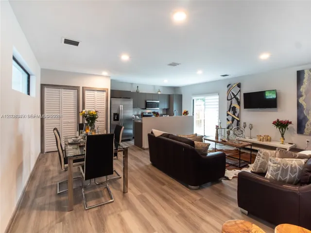 Open-concept interior featuring wood-finish flooring, recessed lighting, neutral wall tones, and floor-to-ceiling louvered closet doors