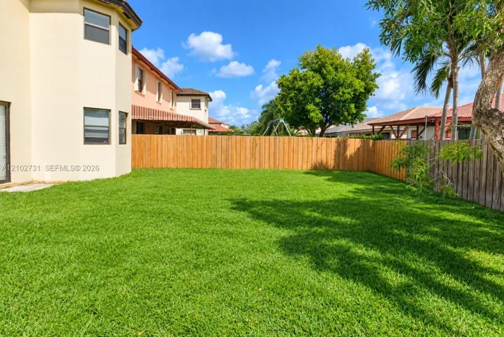Backyard featuring a manicured lawn, full-height wood fencing, and mature landscaping