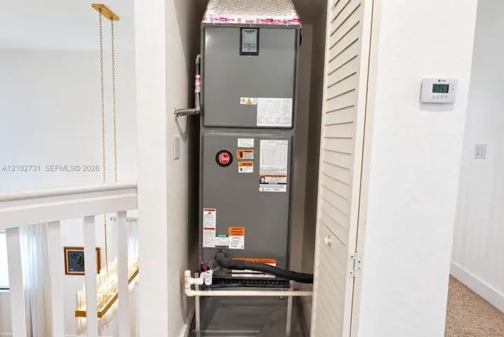 High-efficiency HVAC air handler unit featuring a digital wall-mounted thermostat and louvered closet door enclosure