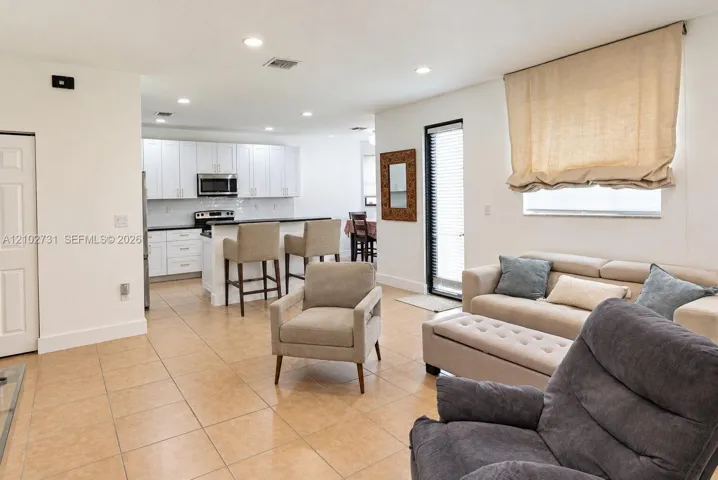 Kitchen featuring white shaker-style cabinetry, a breakfast bar, recessed lighting, and tile flooring